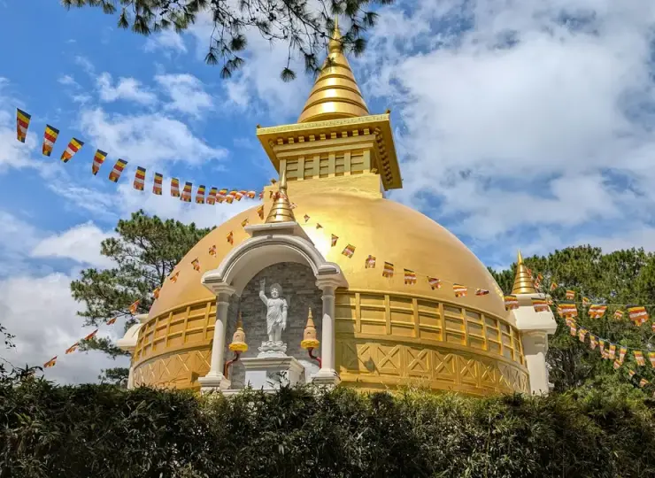 Golden stupa adorned with prayer flags on a hill