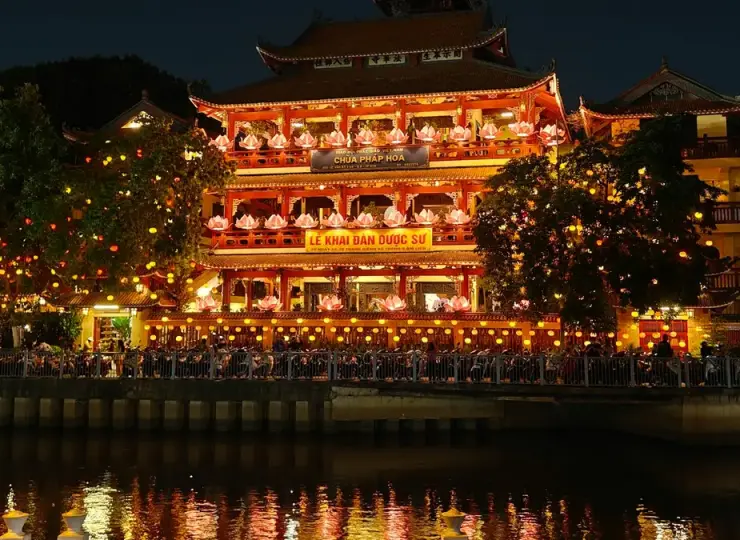 A building lit up at night with lights reflecting in the water