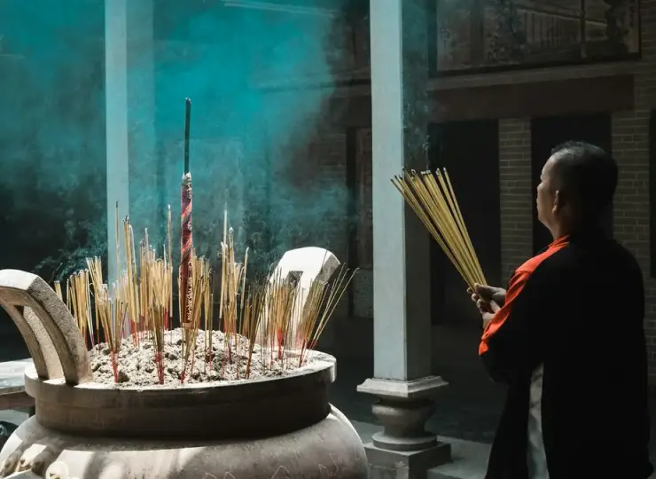Man holding incense sticks inside a temple in Ho Chi Minh City