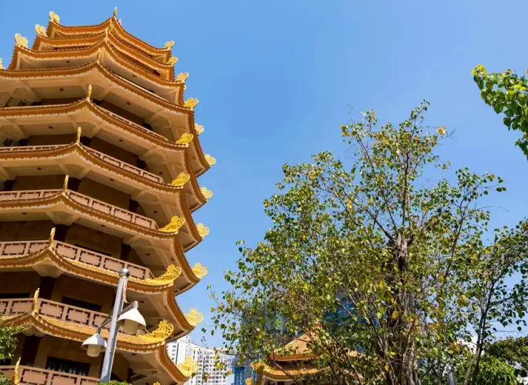 Tall ornate pagoda at the Vietnamese National Buddhist Temple against a blue sky in Ho Chi Minh City