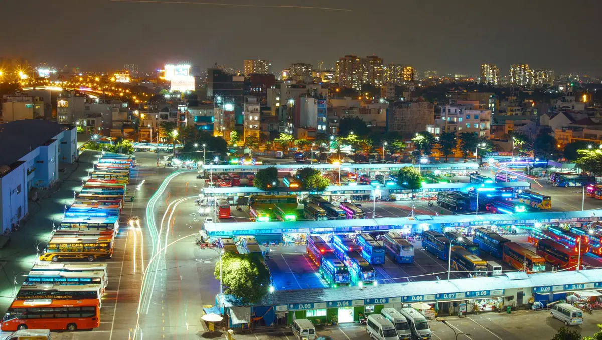 Sleeper buses at a brightly lit Ho Chi Minh City bus terminal at night