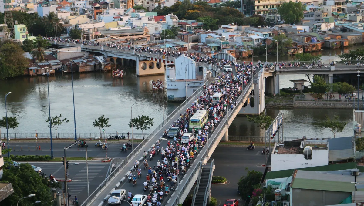 Motorbikes and cars crossing a canal bridge in Ho Chi Minh City, seen from above