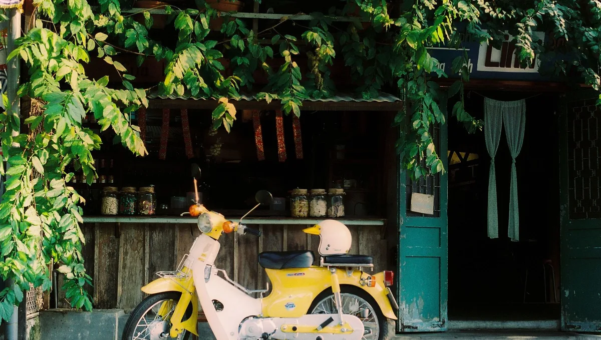 Yellow Honda Cub scooter with a helmet parked outside a wooden shopfront in Vietnam