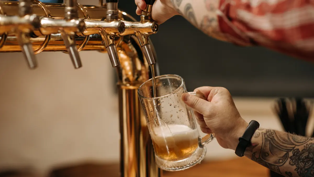 Bartender pouring craft beer from a tap into a glass mug