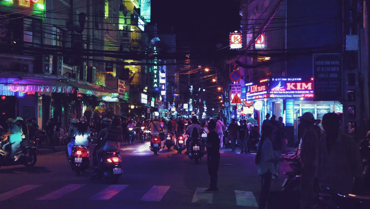 Busy Vietnamese city street with motorcycles and neon lights at night