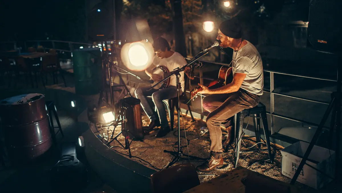 Two musicians performing acoustic live music with guitars at night