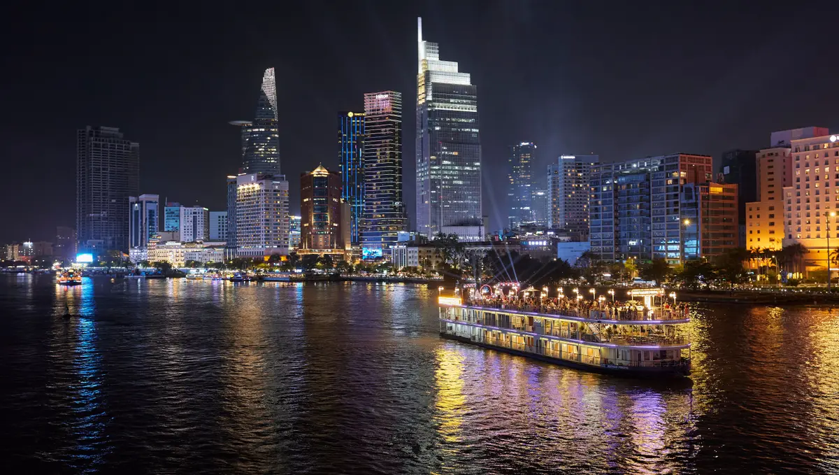 Illuminated Ho Chi Minh City skyline and a dinner boat on the Saigon River at night