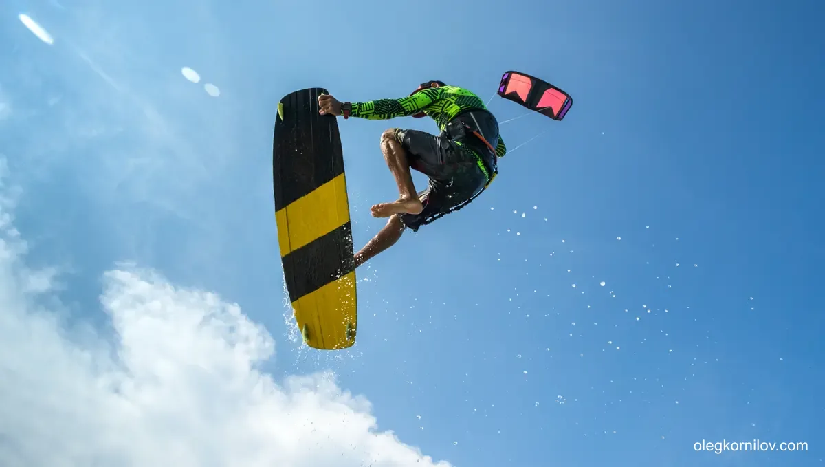 Kitesurfer holding a twin-tip board during an aerial maneuver