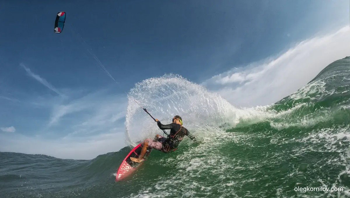 Kitesurfer carving across a steep wind-driven wave