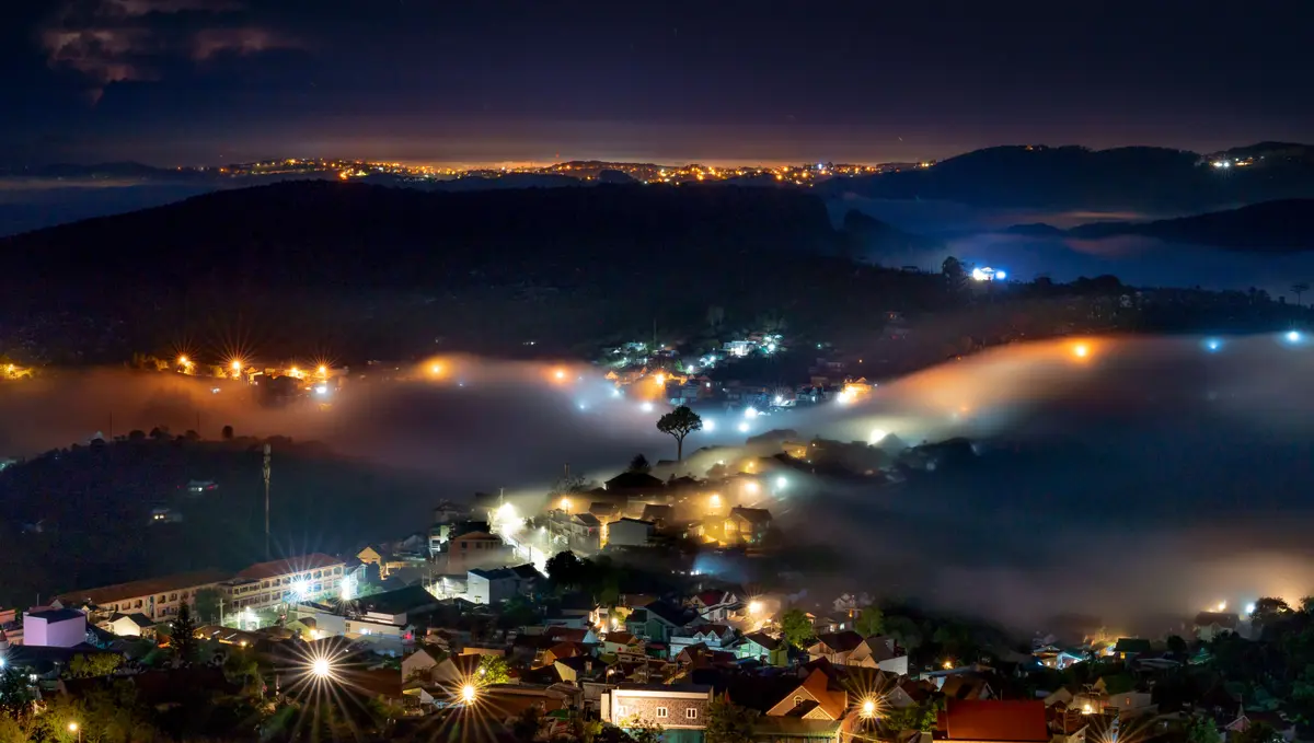 Da Lat hillside homes glowing through mist at night