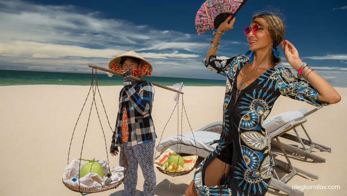 Traveler with a handheld fan beside a beach vendor in Central Ham Tien, Mui Ne